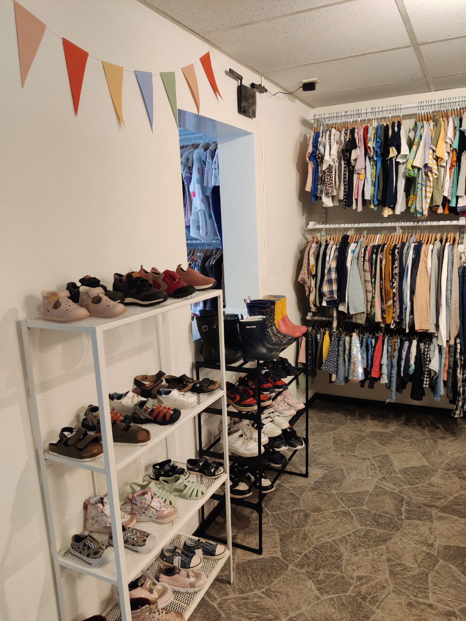 Välorganiserad butik med skor och barnkläder sorterade efter kategori