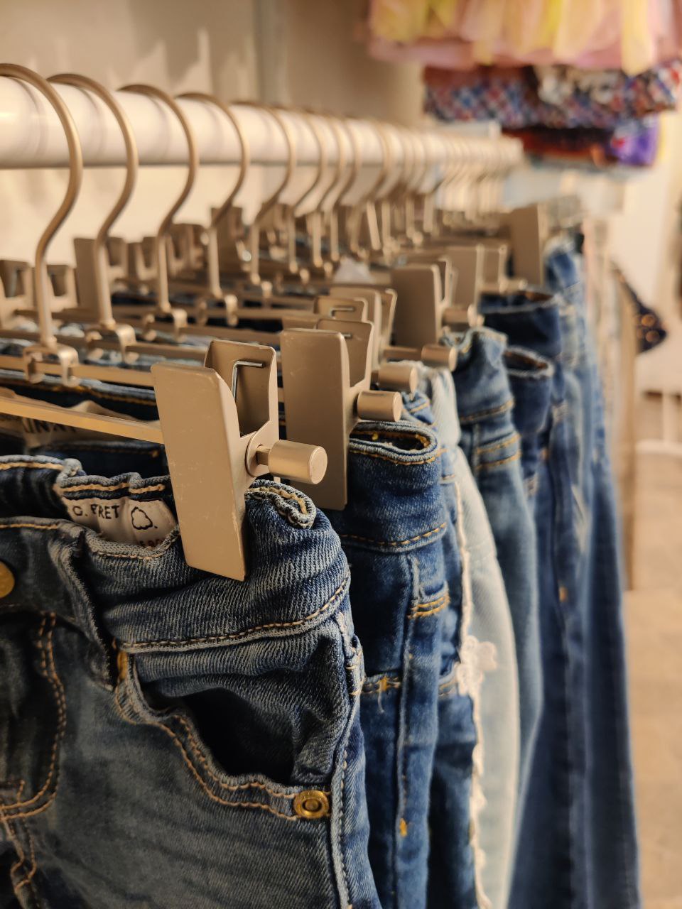 Närbiild på välbevarade jeans som hänger på galgar i butiken